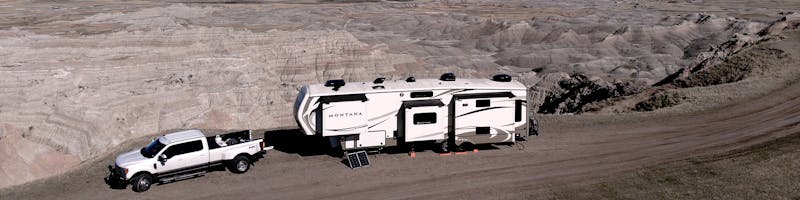 Montana fifth wheel parked in the Badlands with solar panel propped on ground. 