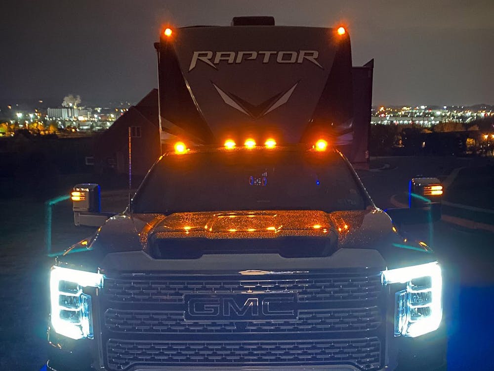 Raptor being hauled by a GMC truck at night with the lights on 