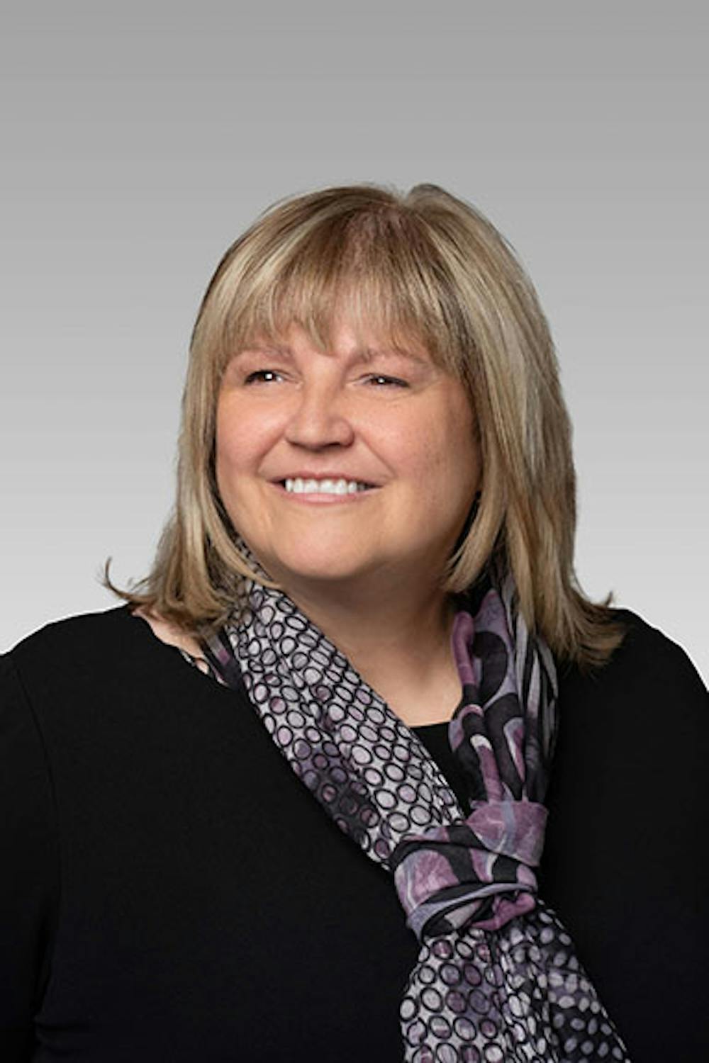 Sheri Hassman-Schuler headshot on a gray gradient backdrop