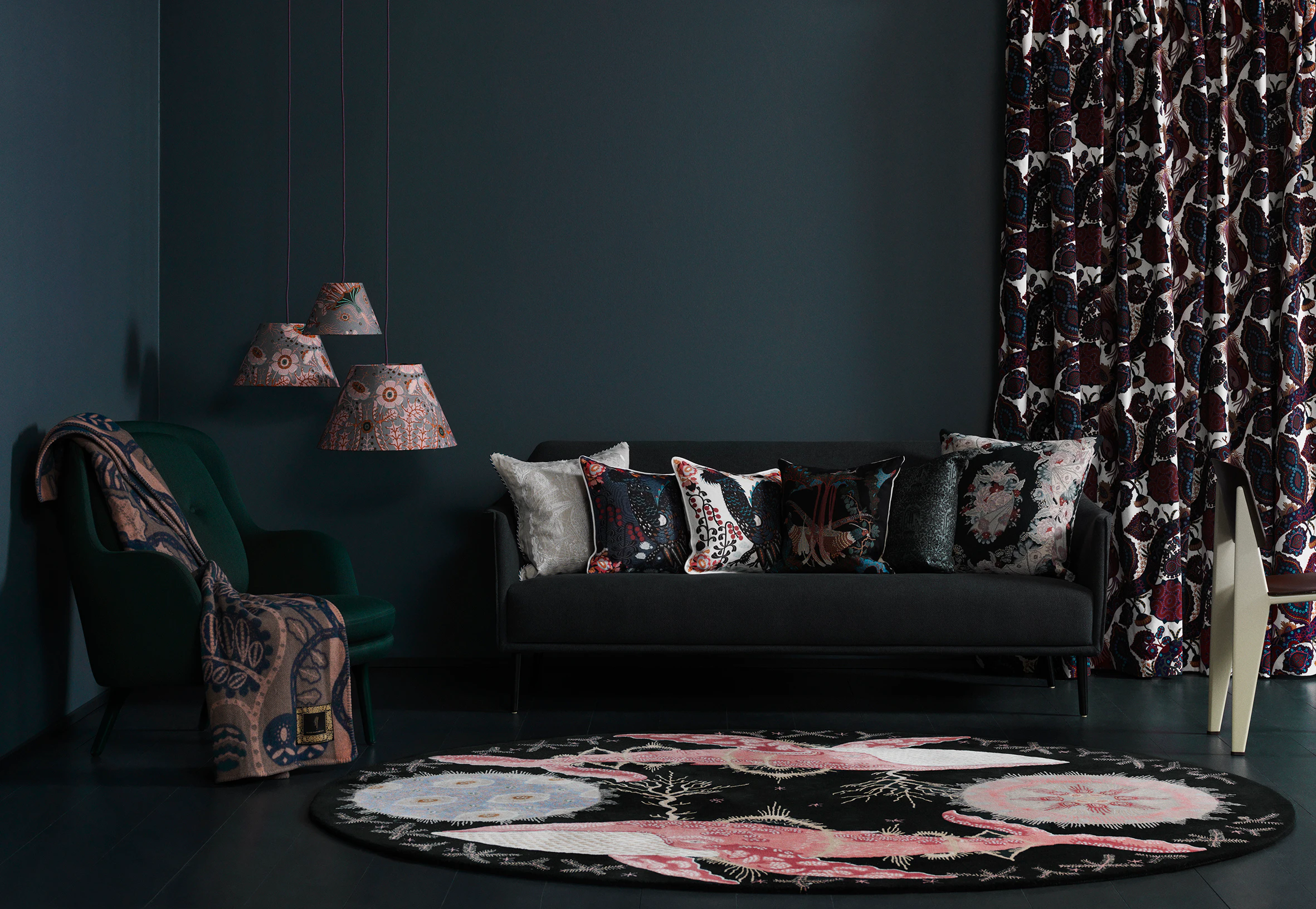 Dark living room with printed velvet cushions on a black sofa, Purple Rain velvet curtains and a round pink and black rug