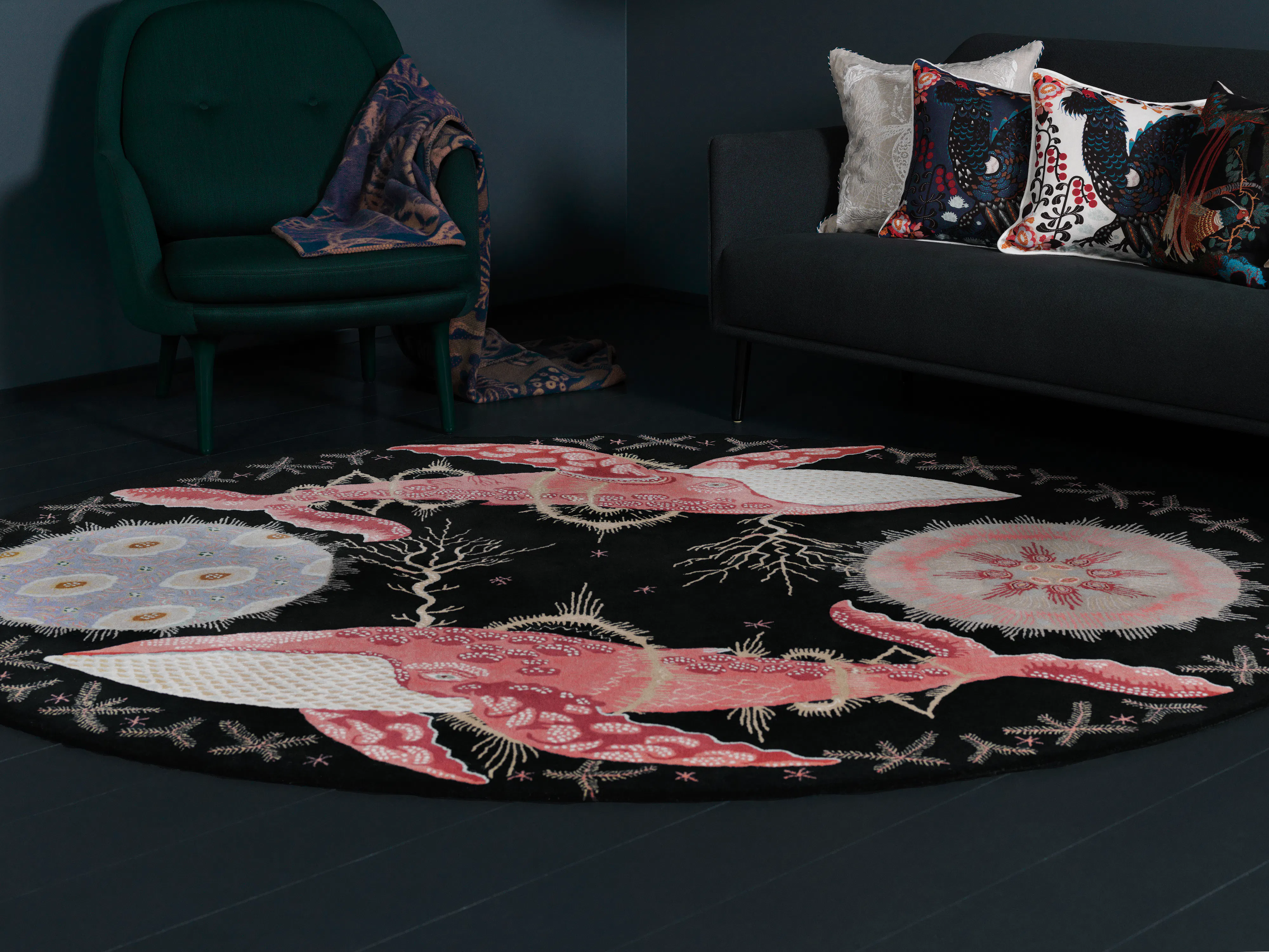 Round Klaus Haapaniemi rug with pink whales on a dark floor, in front of a sofa with printed cushions