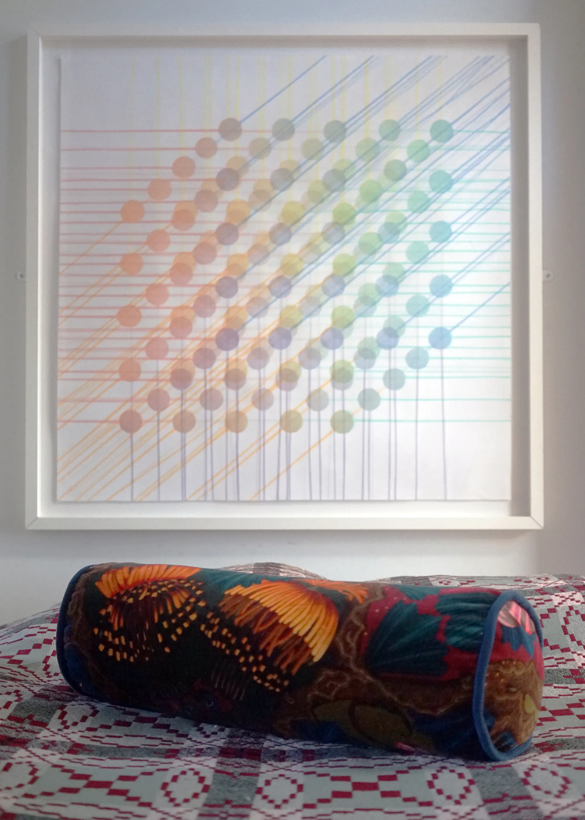 Artemisia Absinthium velvet bolster cushion with orange and red flowers on a bed below a framed artwork