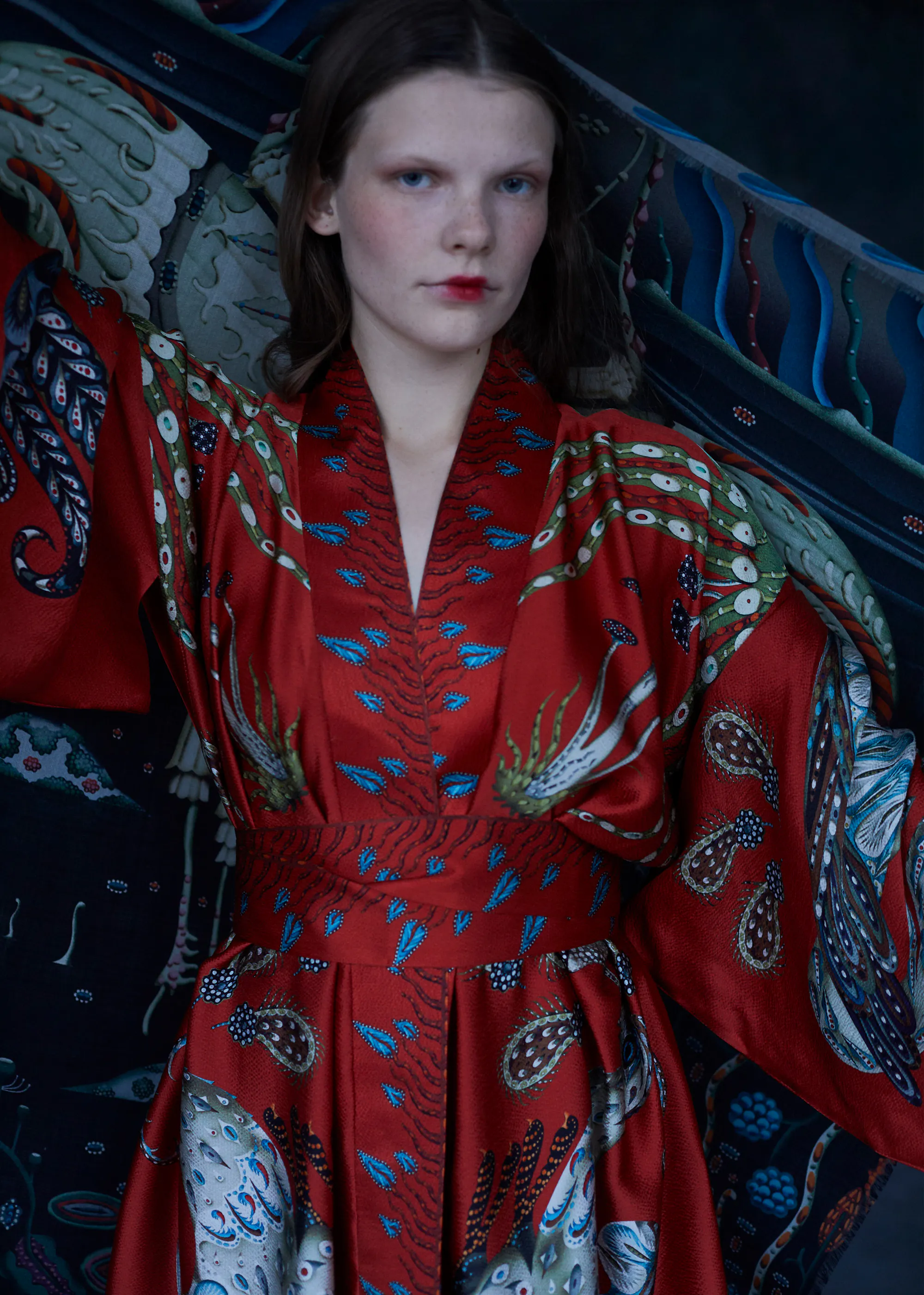 Close-up of the red-orange Firebird kimono belted at the waist, with birds and feathers printed on the wide sleeves