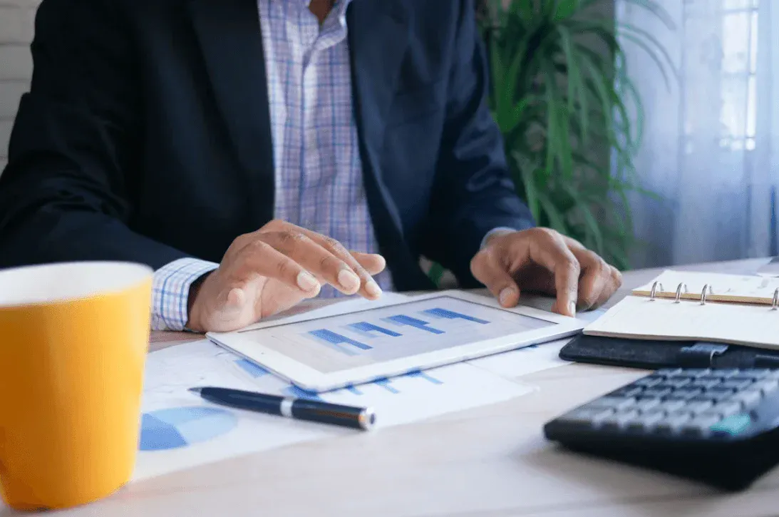 Pessoas em reunião analisando gráficos e números em um documento impresso sobre uma mesa, com calculadora e caneta ao lado, sugerindo planejamento e gestão financeira.