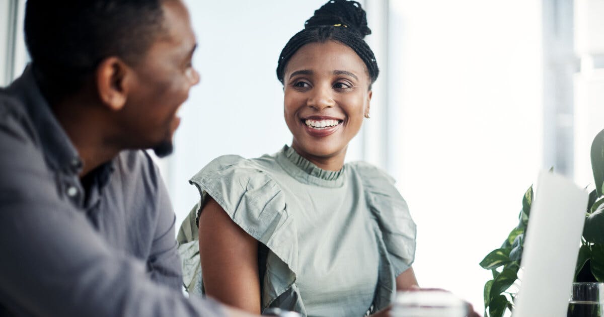 Um homem e uma mulher sorriem um para o outro enquanto estão sentados à mesa.