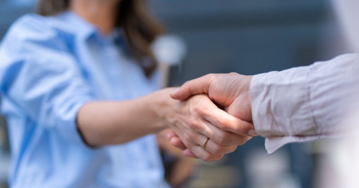 Duas pessoas apertando as mãos em um gesto de cumprimento e acordo, simbolizando colaboração e entendimento mútuo.