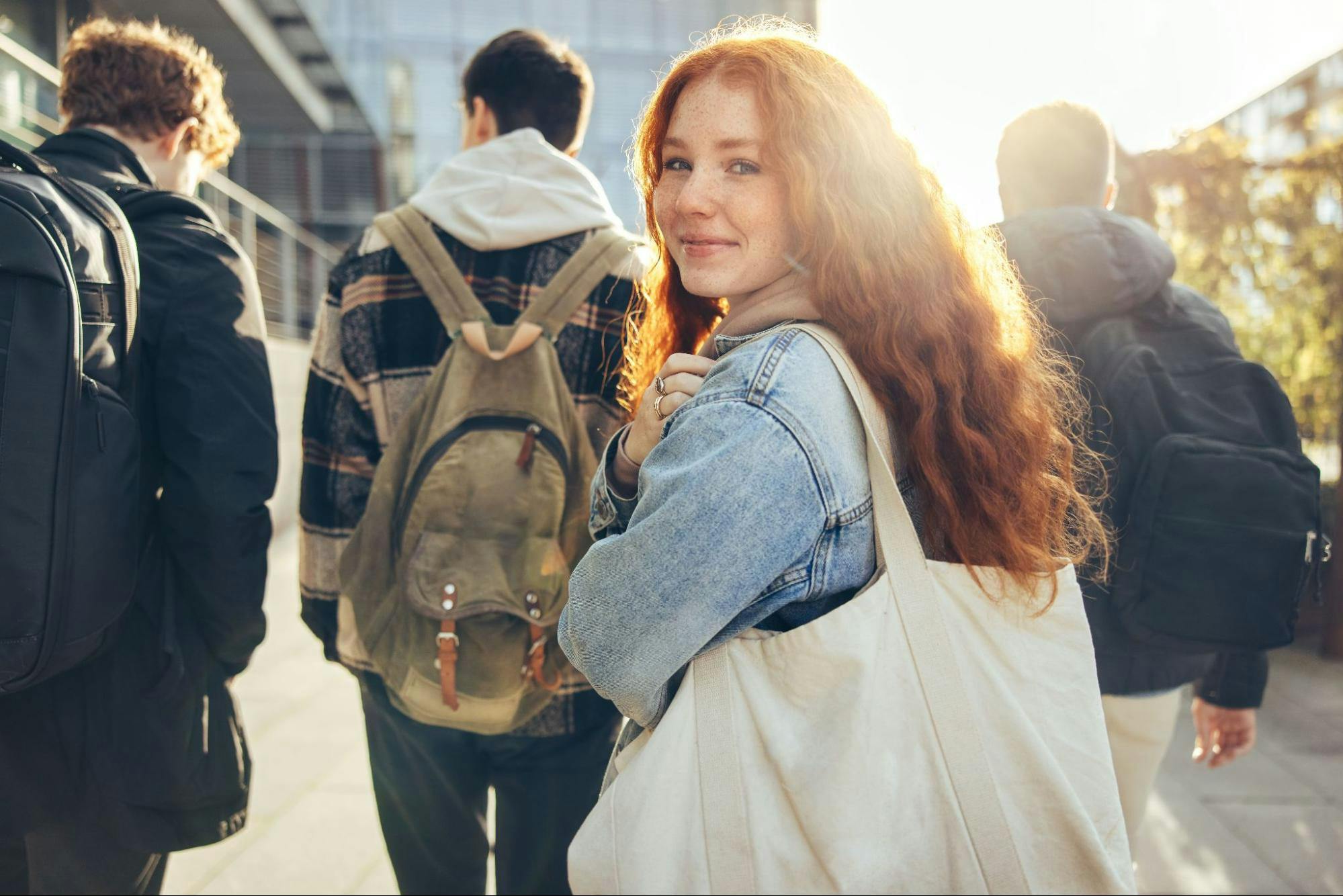 Mulher ruiva olhando para a câmera enquanto três garotos andam atrás dela