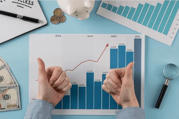 Pessoa fazendo positivo com os dois dedos e abaixo uma planilha com gráficos