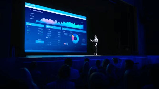 Uma mulher realizando uma apresentação de um dashboard em um grande palco