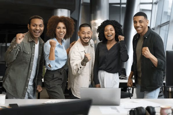 Várias pessoas felizes e sorrindo uma do lado da outra e fazendo um sinal de punho fechado comemorando