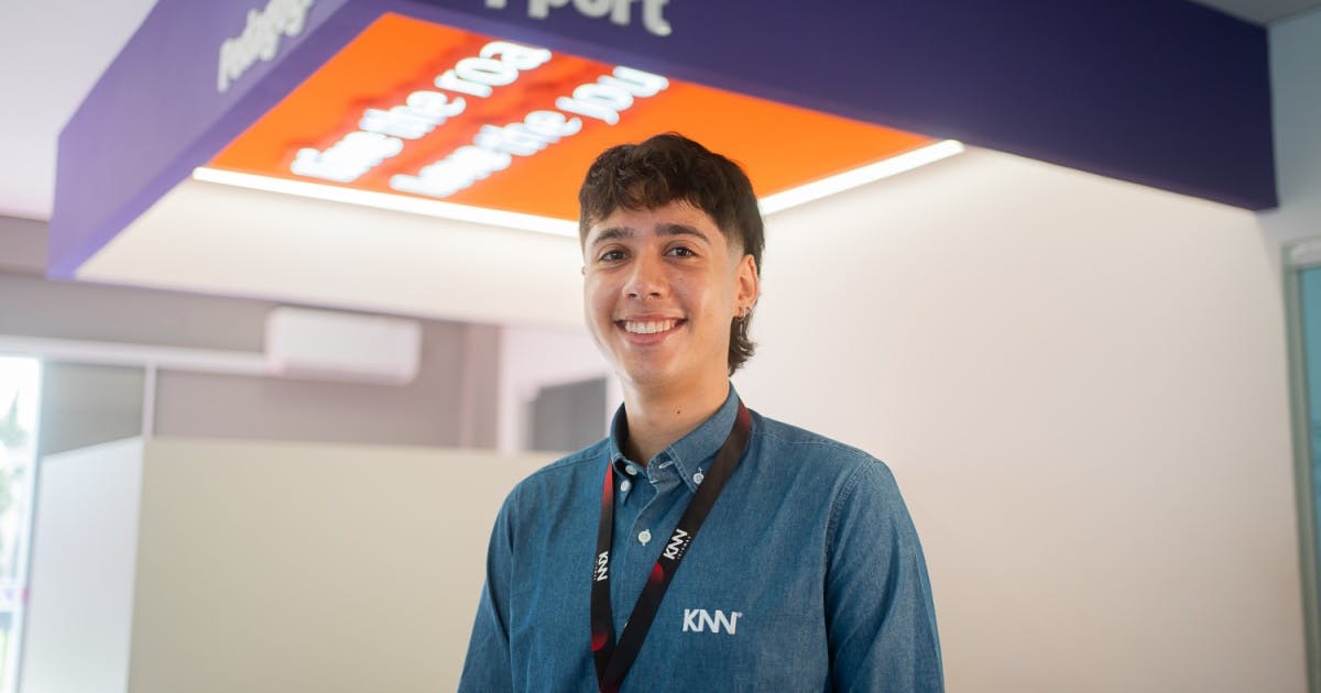 Um professor sorrindo com camiseta social e crachá da KNN Idiomas.