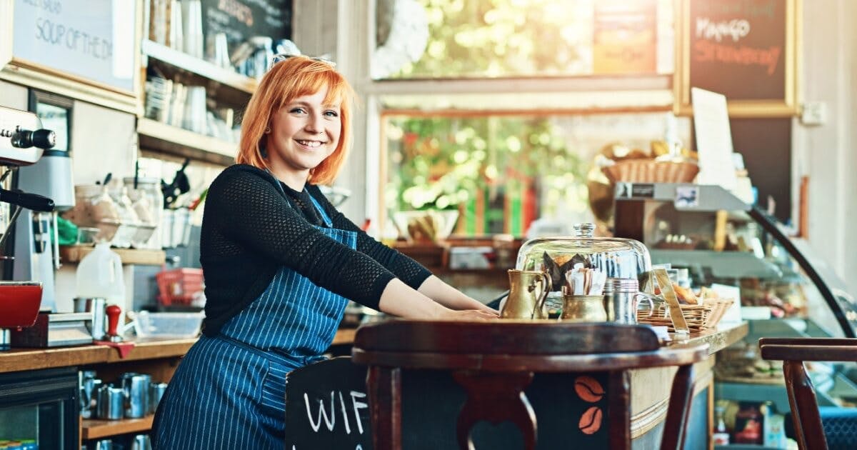 Mulher ruiva com um avental sorrindo e olhando para a câmera.