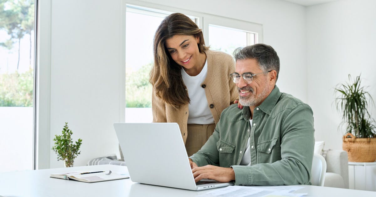 Um homem e uma mulher observam atentamente a tela de um laptop, demonstrando interesse e colaboração.