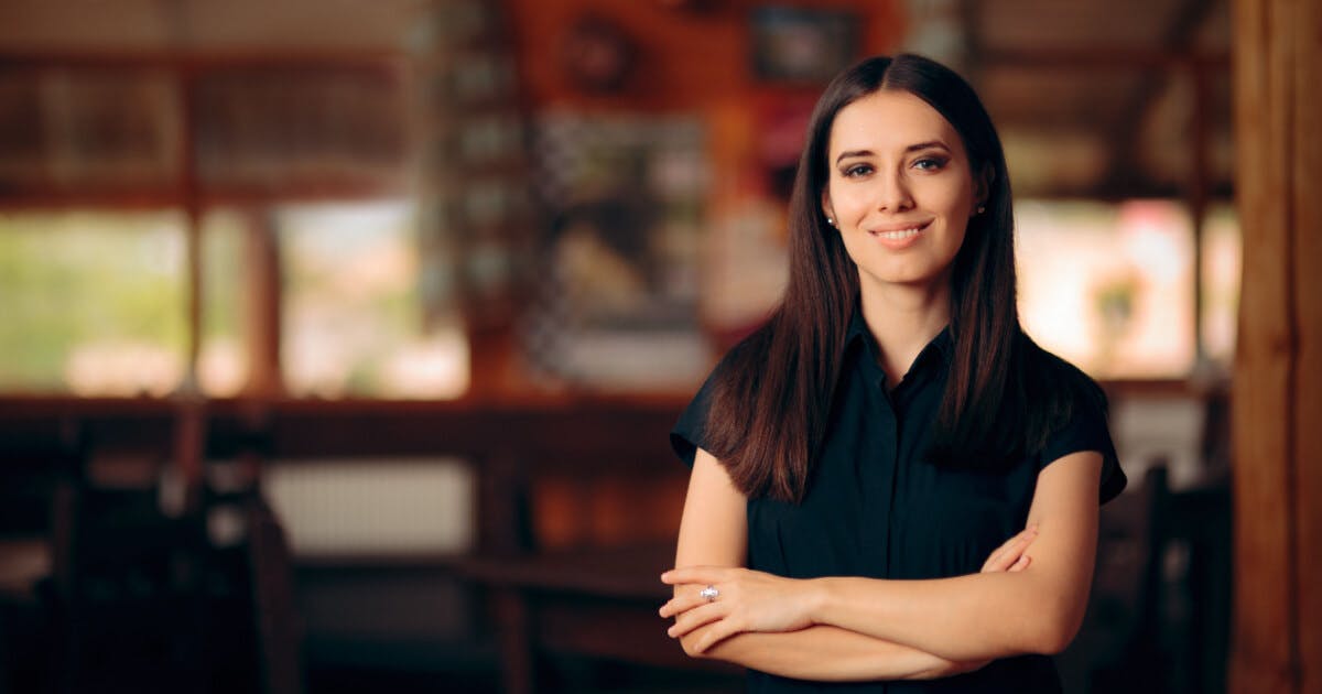 Uma mulher com camisa preta está em pé diante de uma mesa.