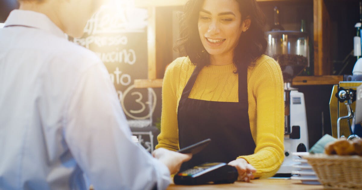 Uma mulher sorri para o caixa enquanto realiza uma compra.