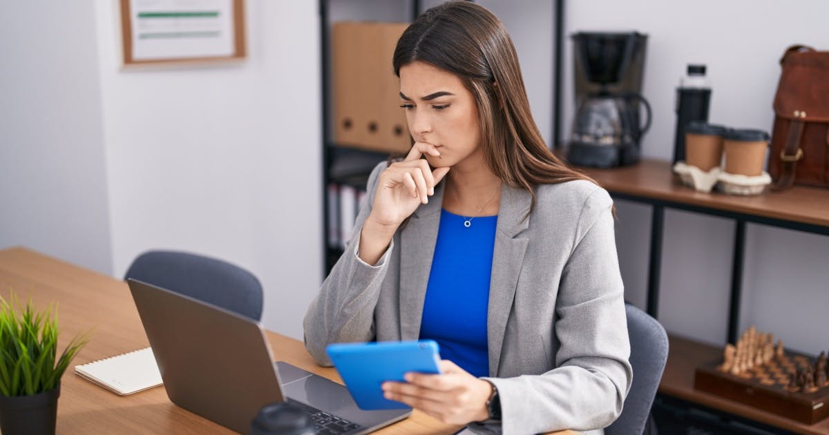 Mulher com a mão na boca e expressão de preocupação olhando para um notebook.