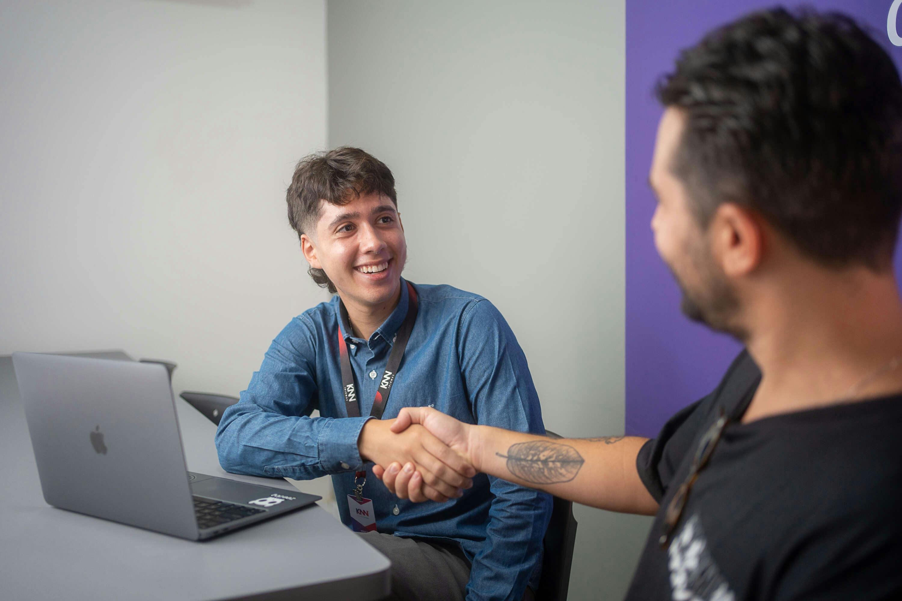 Dois homens sorrindo e se cumprimentando.