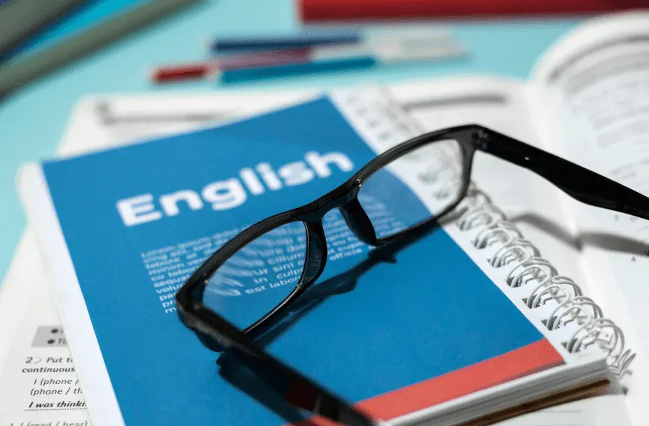 Livro de inglês com óculos sobre uma mesa, ideal para estudar e aprender inglês de forma eficiente e prática.