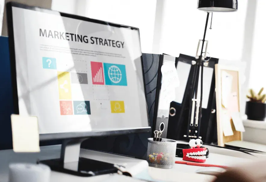 Imagem de um escritório com computador exibindo uma estratégia de marketing, incluindo gráficos e ícones, ideal para negócios e profissionais de marketing digital.