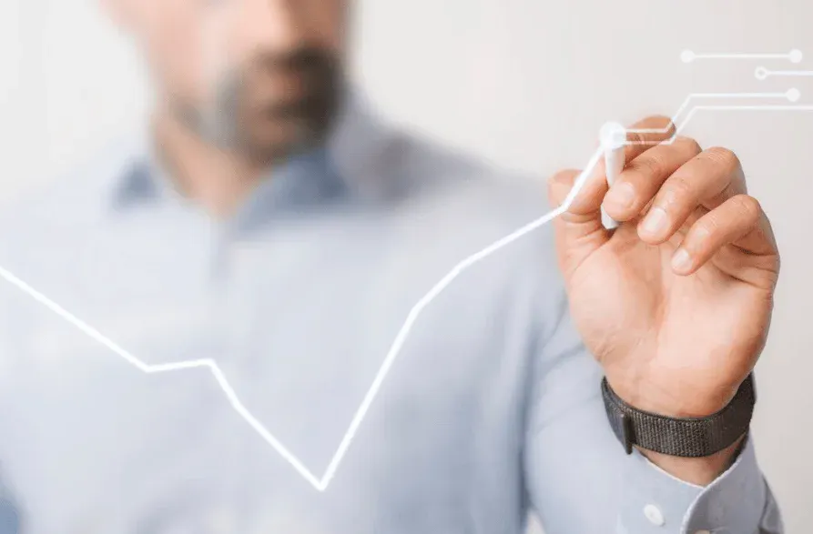 Homem desenhando uma linha de crescimento de lucro ou progresso usando uma caneta em um fundo desfocado. Representa crescimento de negócios, análise de dados ou sucesso financeiro.