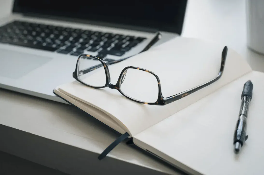 Computador com caderno e óculos