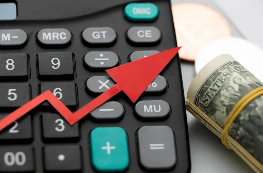 Calculadora financeira com gráfico em seta vermelha apontando para cima e notas de dólar ao lado, sugerindo crescimento de investimentos e resultados positivos.