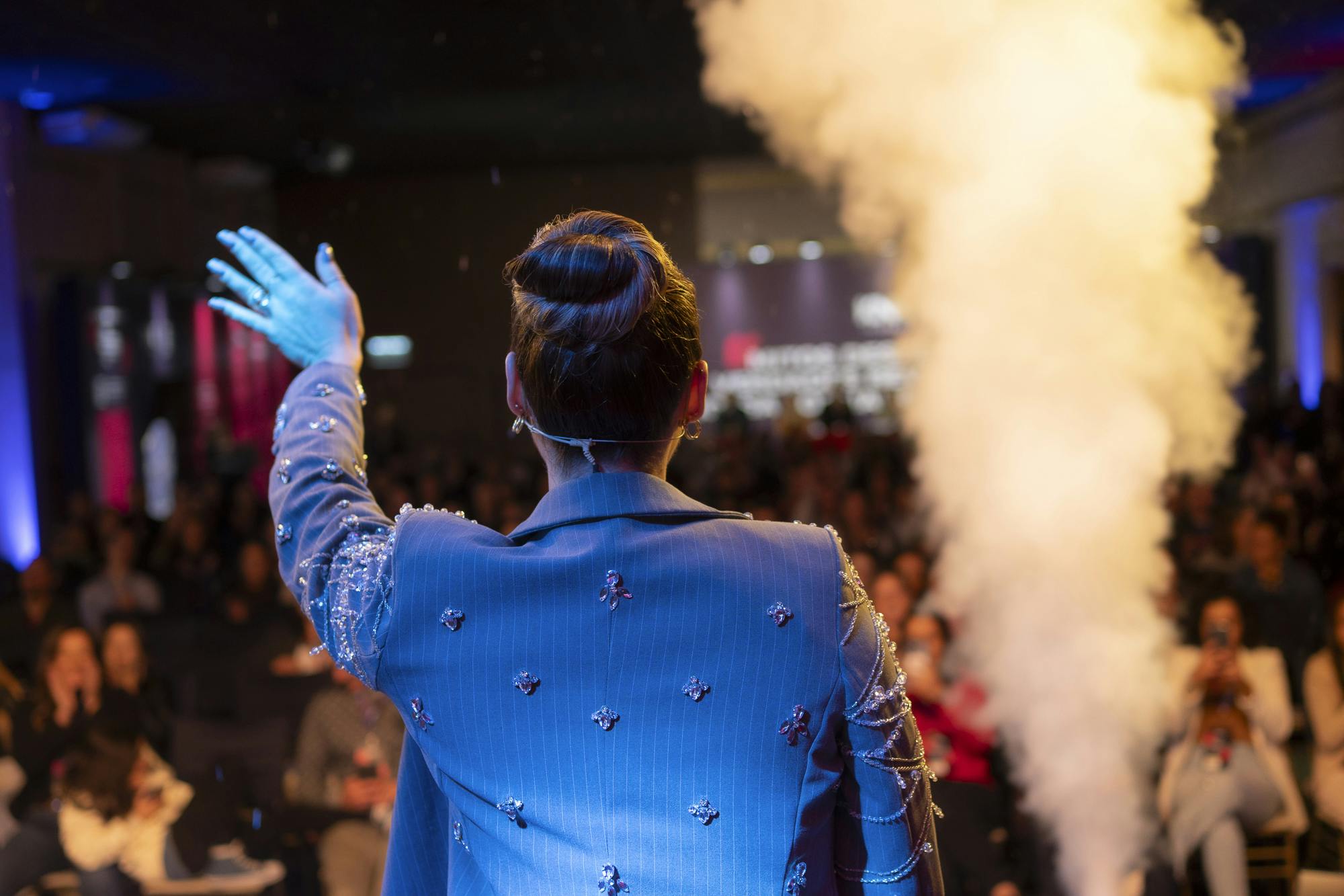 Foto da Geiza Boeira no palco acenando para os franqueados na Convenção Mitos e Verdades 2024.