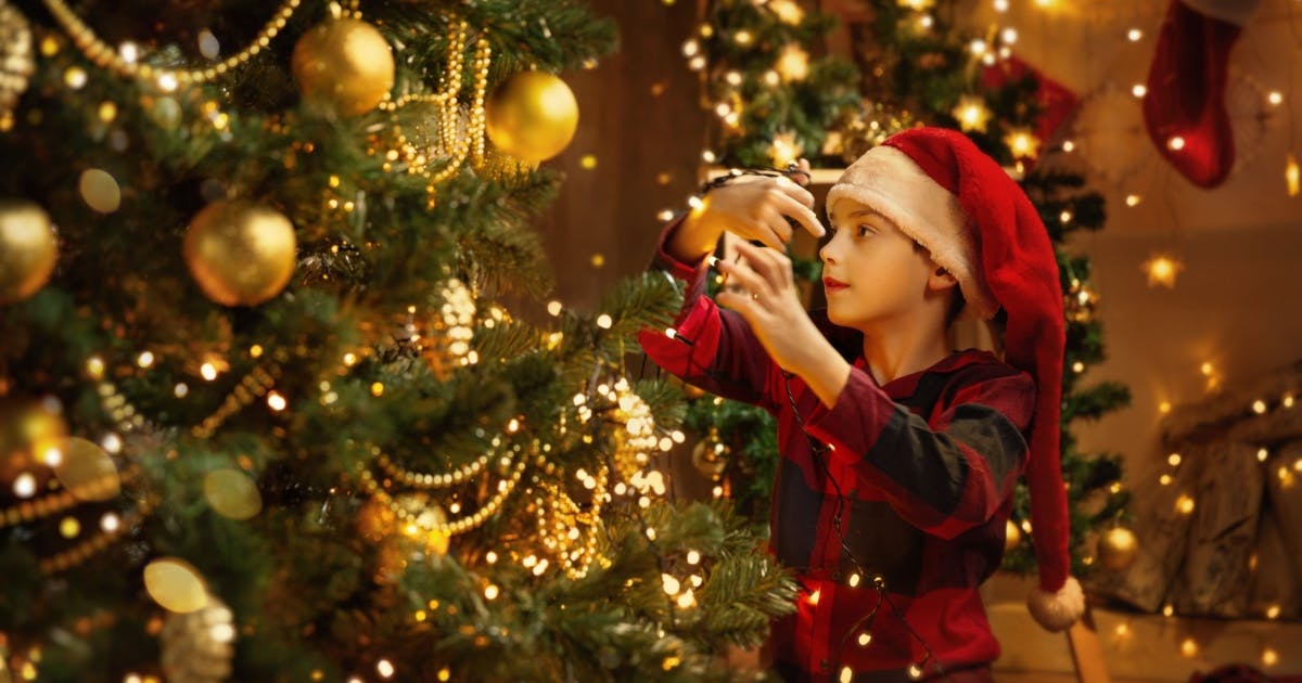 Fotos de uma criança com roupa de natal encostando em uma árvore de Natal.