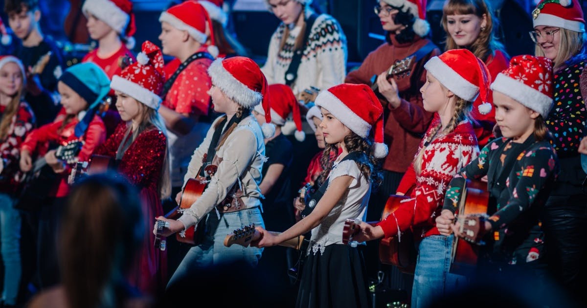 Crianças vestidas com roupas de Natal em uma apresentação.