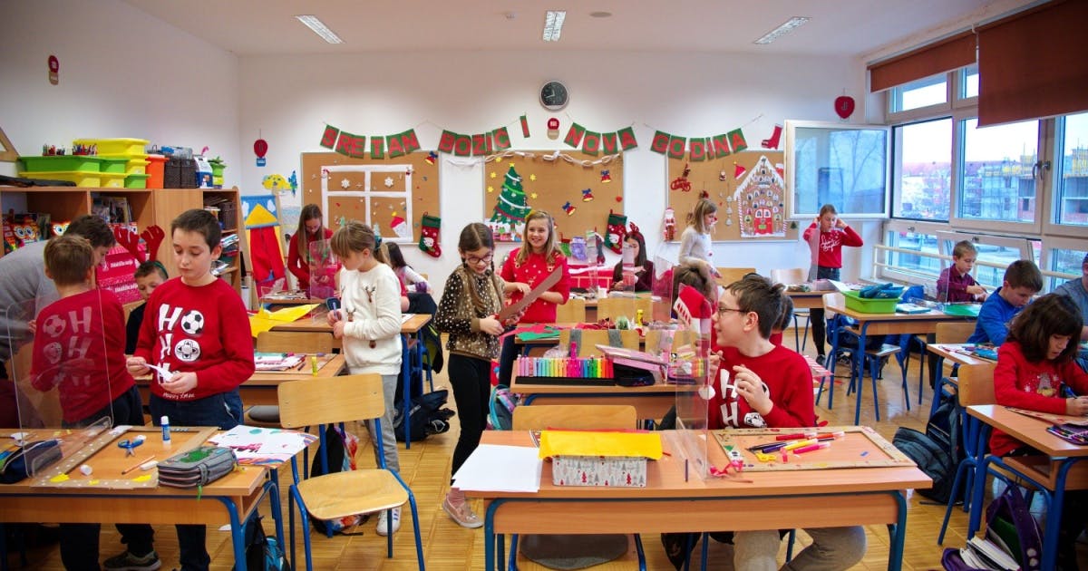 Crianças decorando uma sala de aula com decoração de natalina.