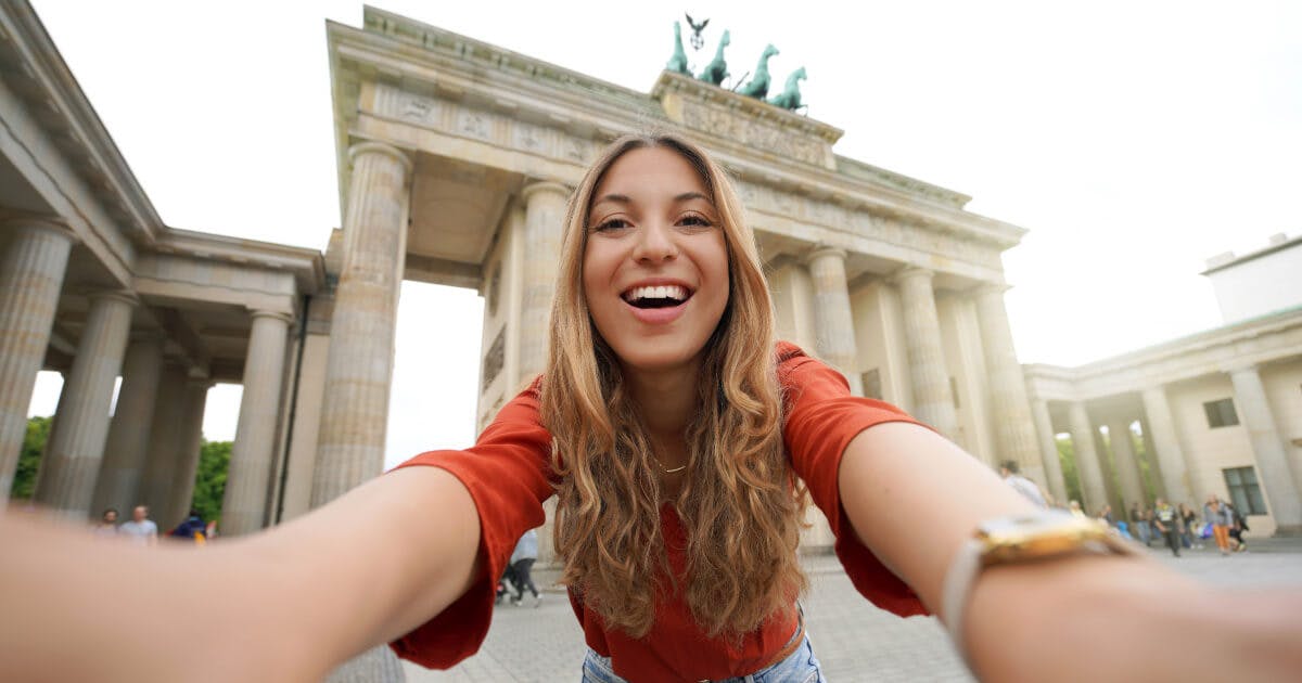 Uma mulher tirando uma selfie em frente ao Portão de Brandemburgo.