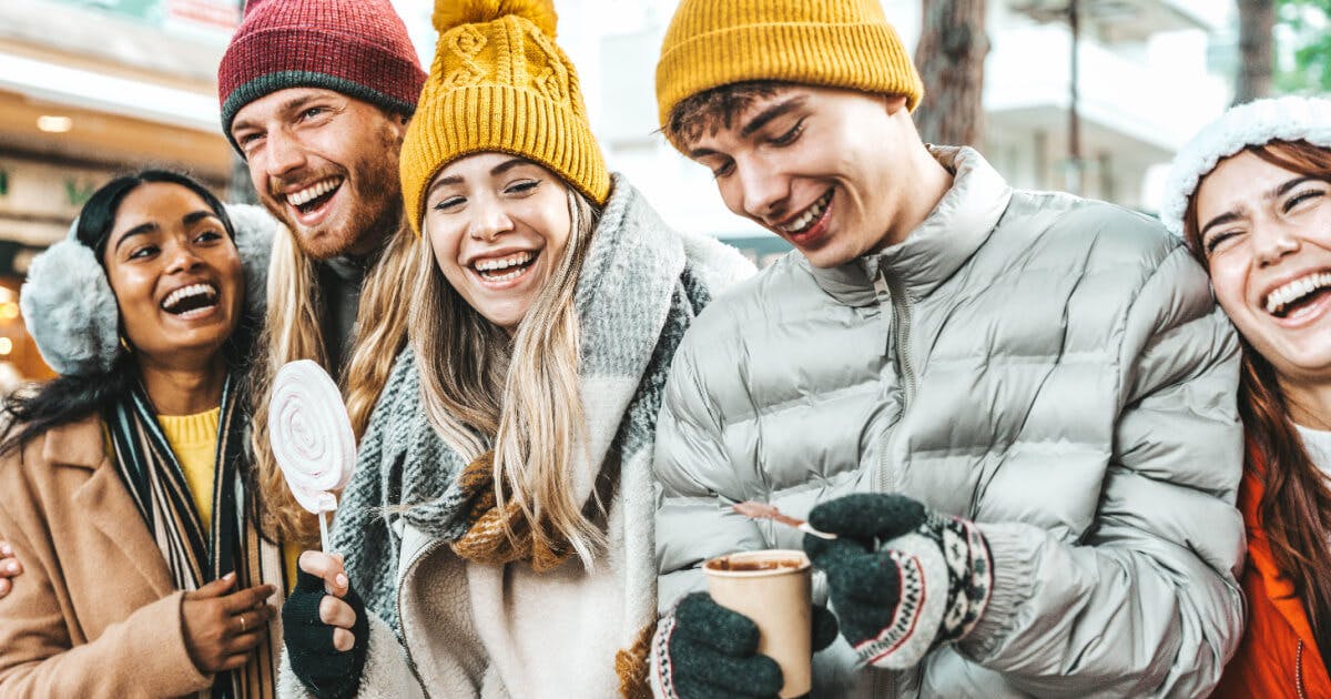 Grupo de jovens sorrindo enquanto seguram xícaras de café, transmitindo alegria e descontração.