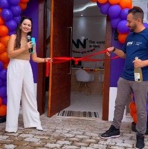 Foto dos franqueados Lilian e Thiago da KNN Idiomas com uma fita de presente na mão, no dia da inauguração da escola.