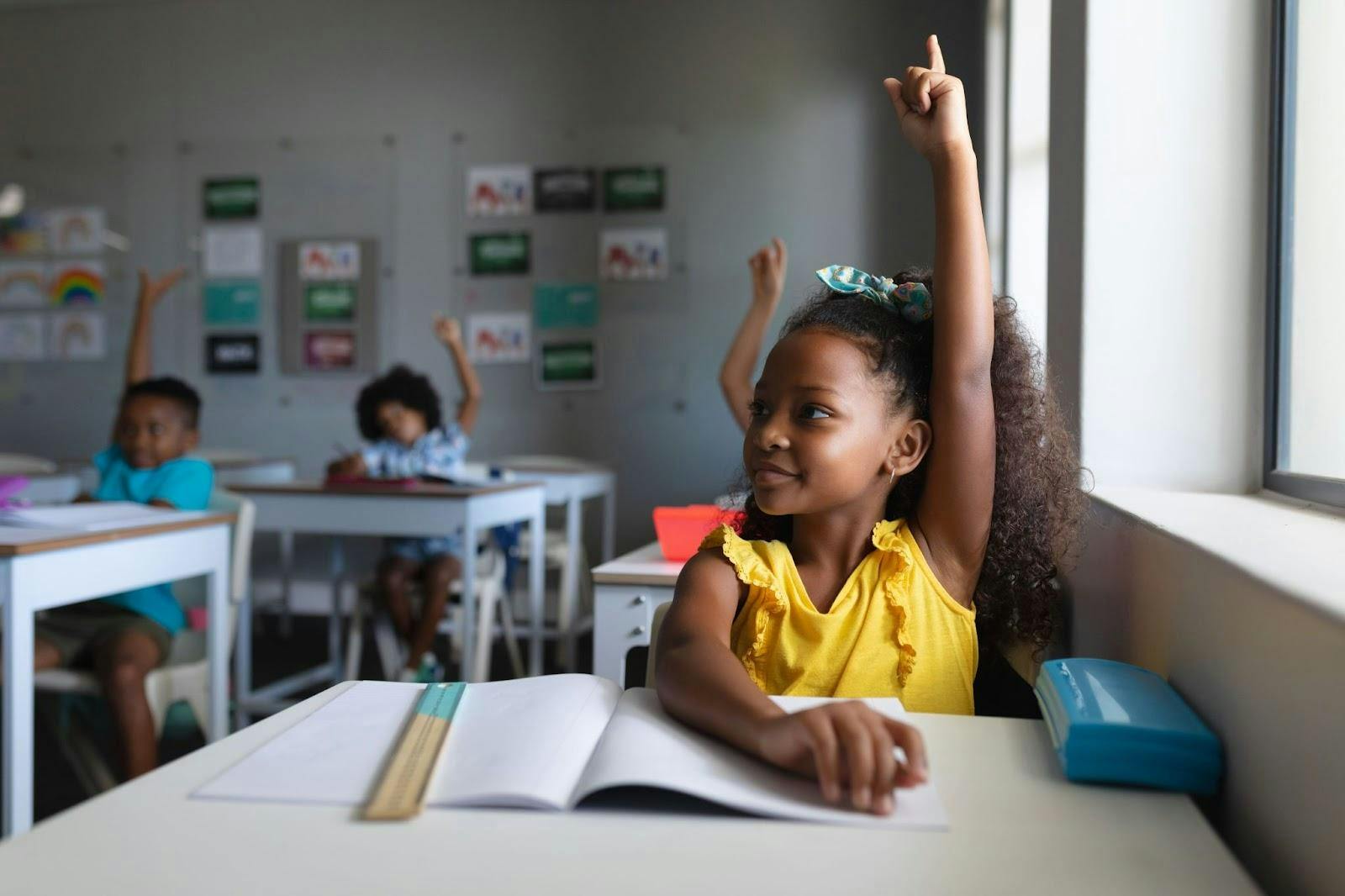 Criança com a mão erguida na sala de aula