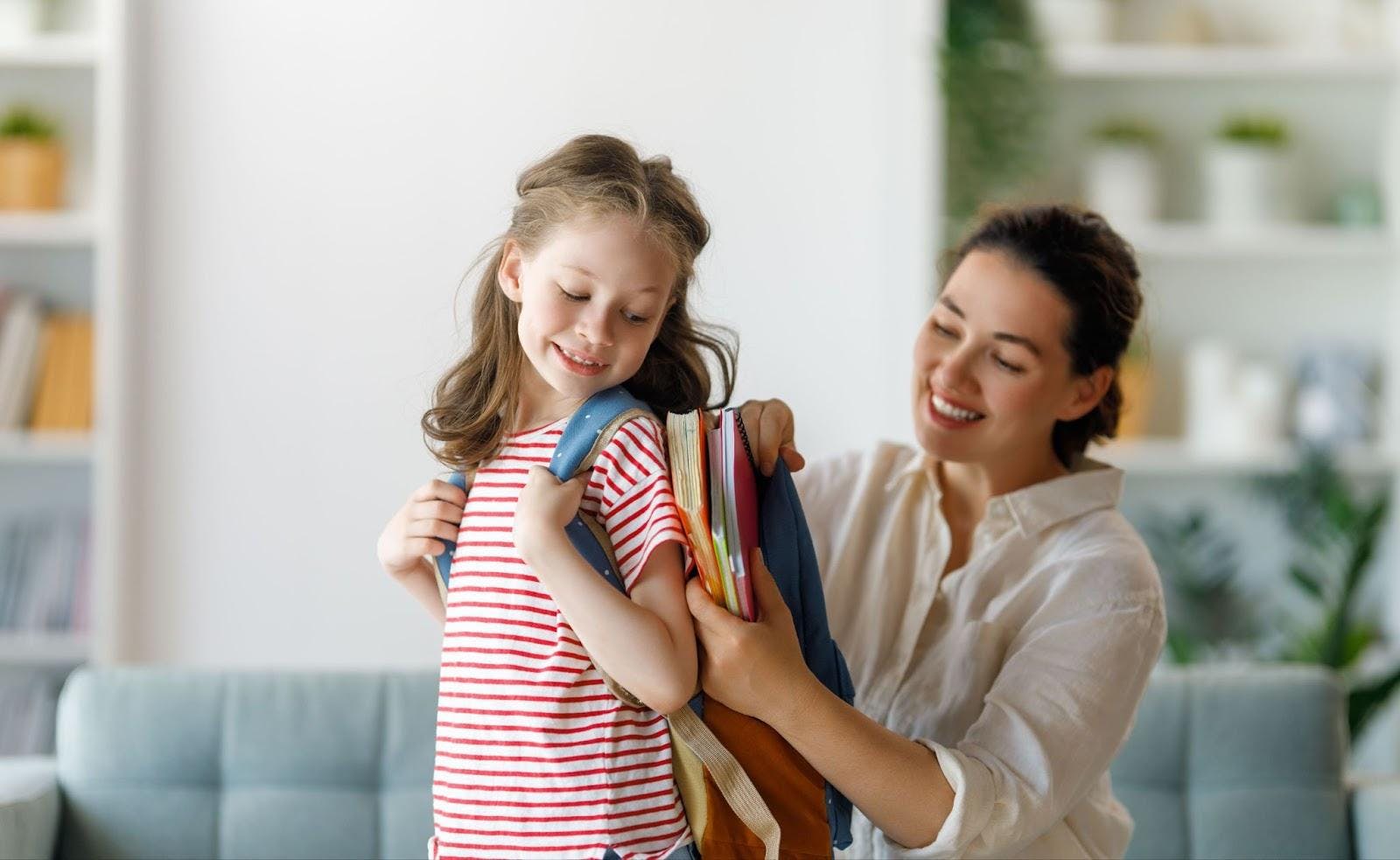 Mãe arrumando mochila nas costas da filha