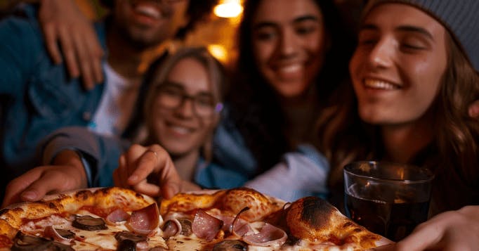 Pessoas olhando e apontando o dedo para uma pizza felizes da vida