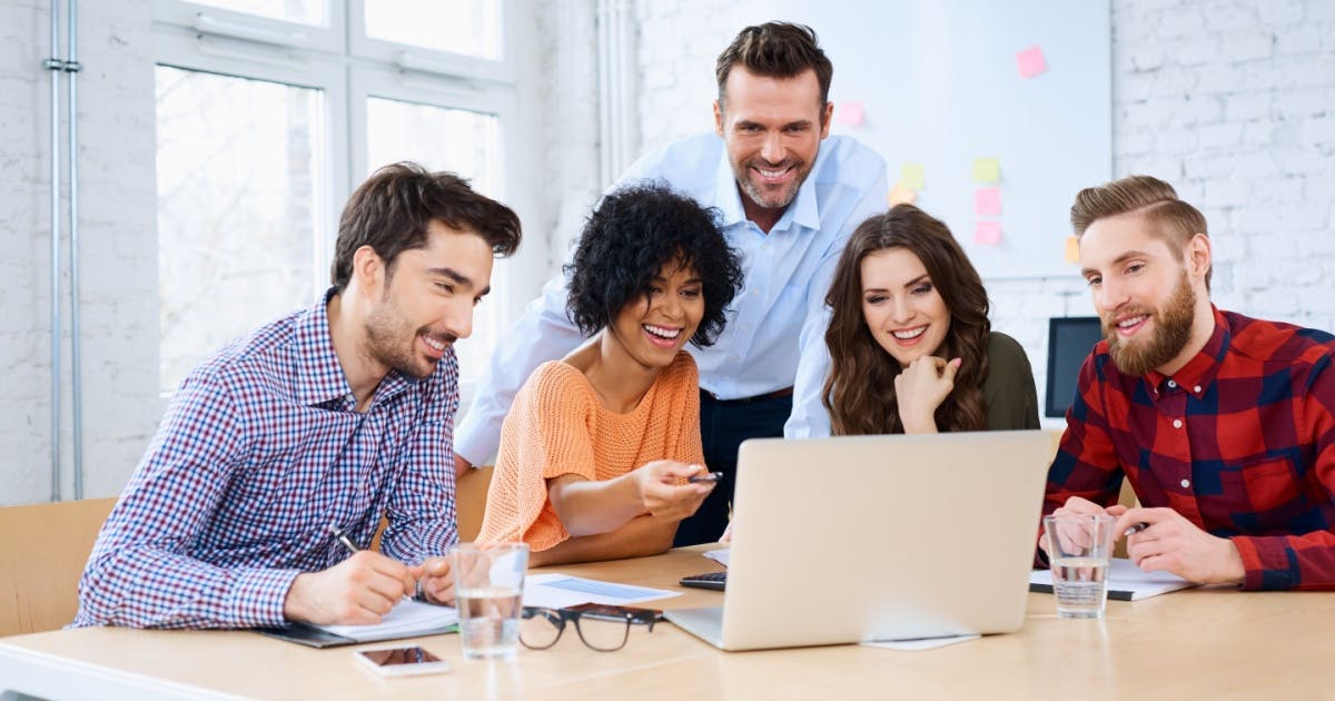 Professores recebendo treinamento e olhando para a tela de um notebook.