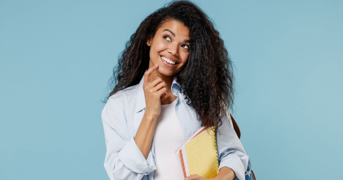 Mulher sorrindo e olhando para cima com um livro na mão.