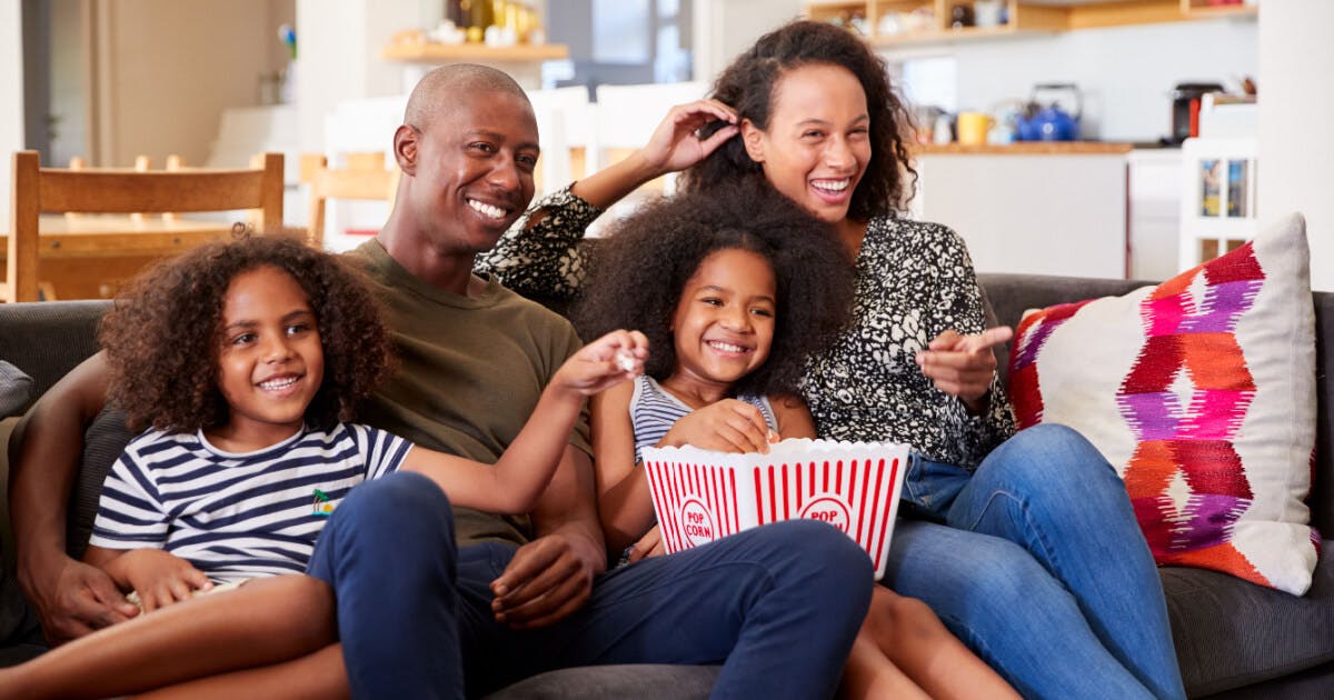 Uma família reunida no sofá, assistindo televisão e desfrutando de momentos juntos.