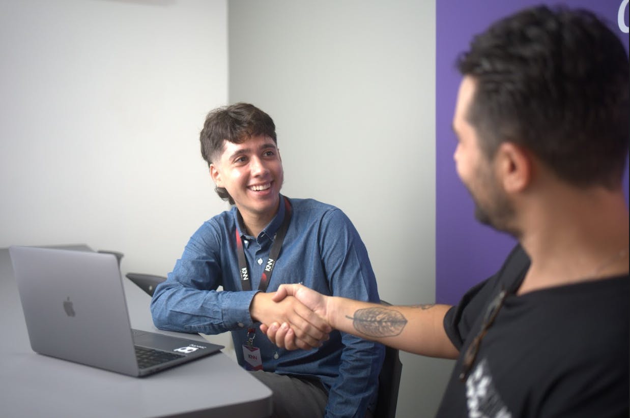 Dois homens dando as mãos com expressão de alegria.