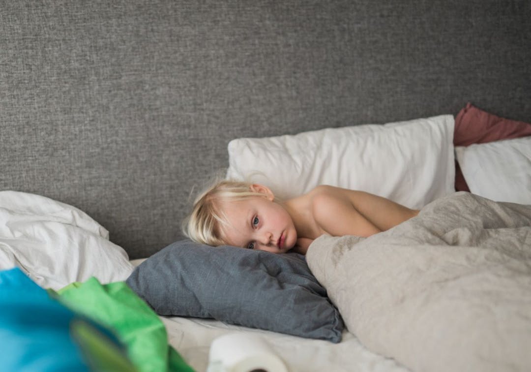 barn ligger i sängen sjuk