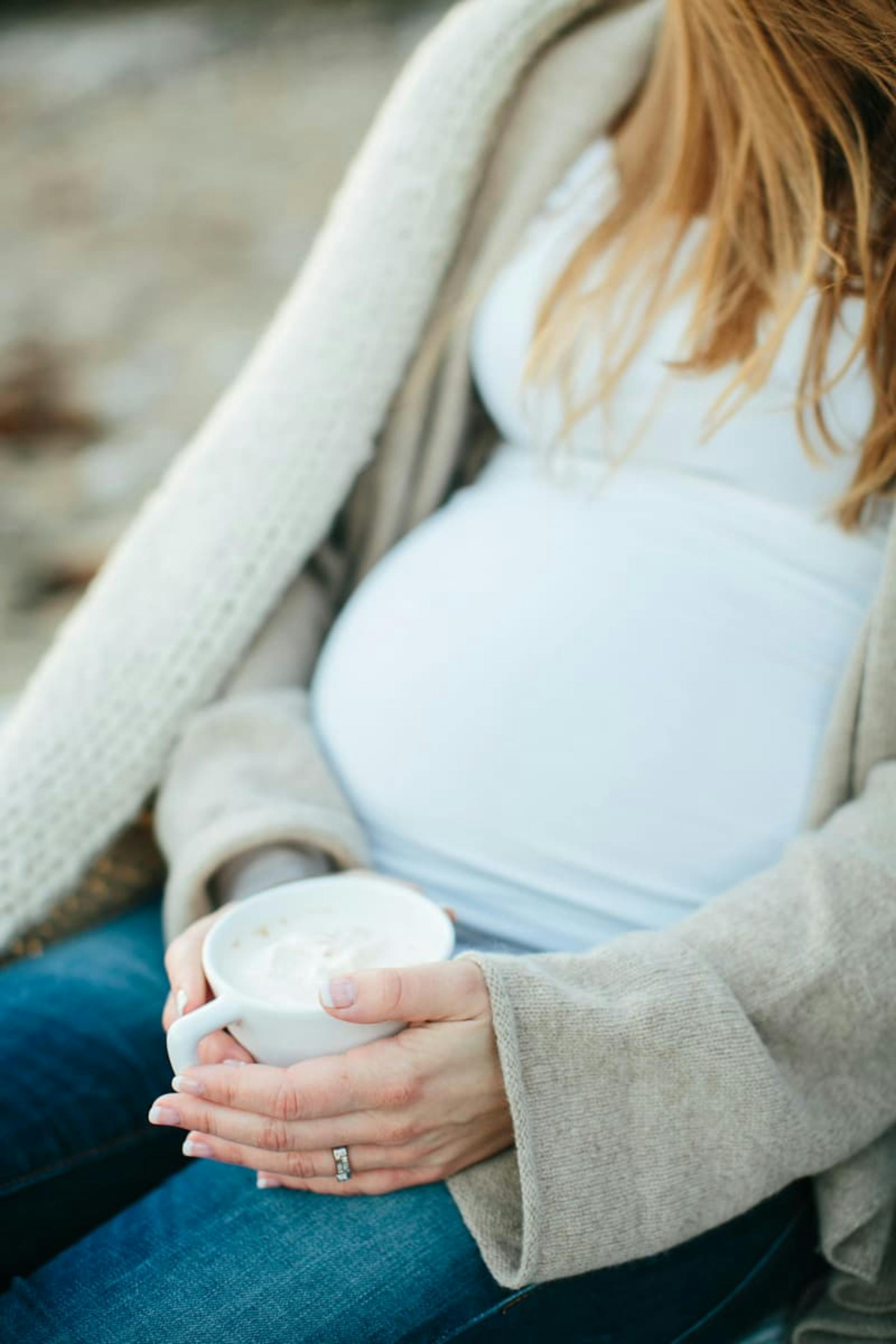 gravid kvinna håller i en kaffekopp