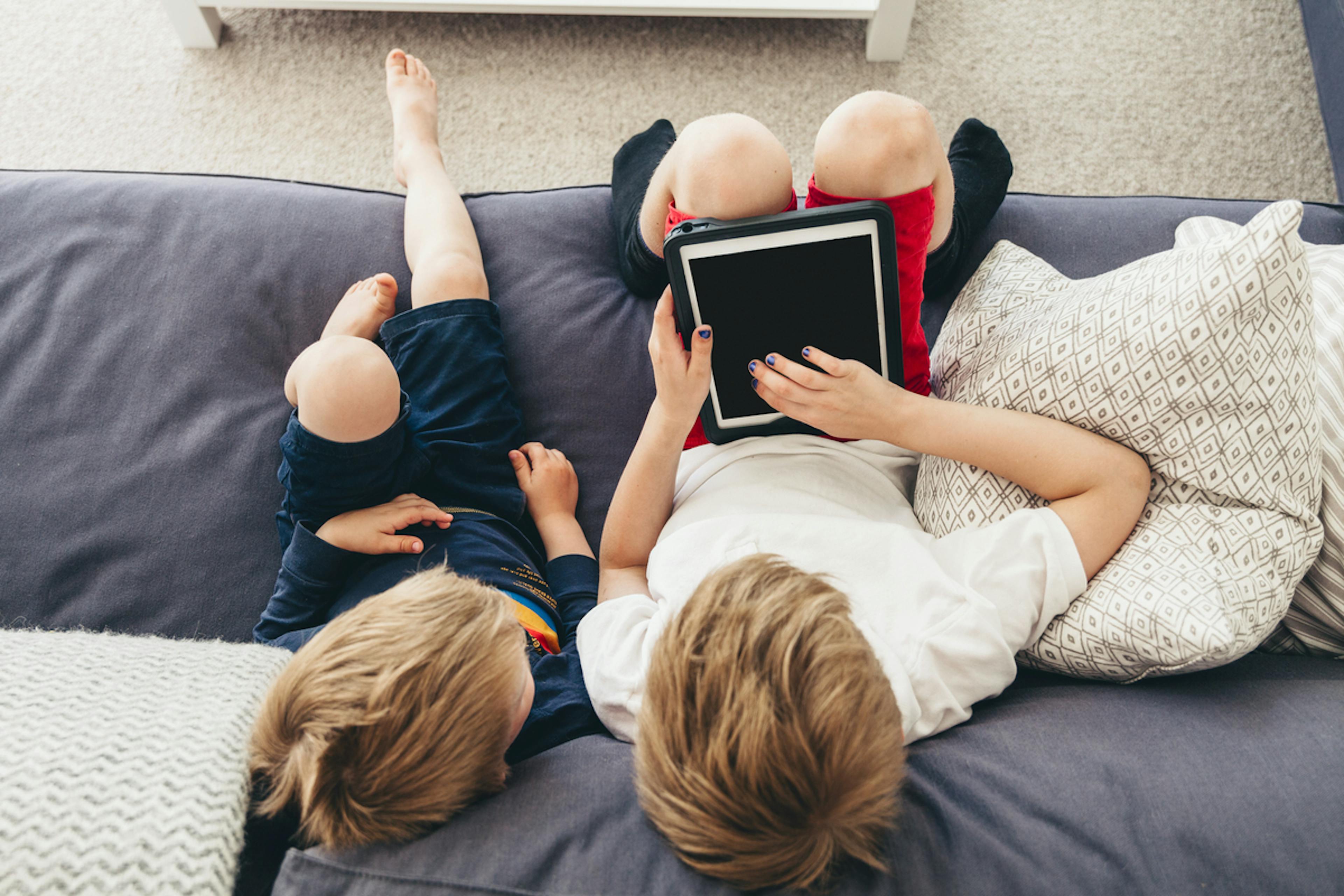 två barn sitter i soffa med ipad