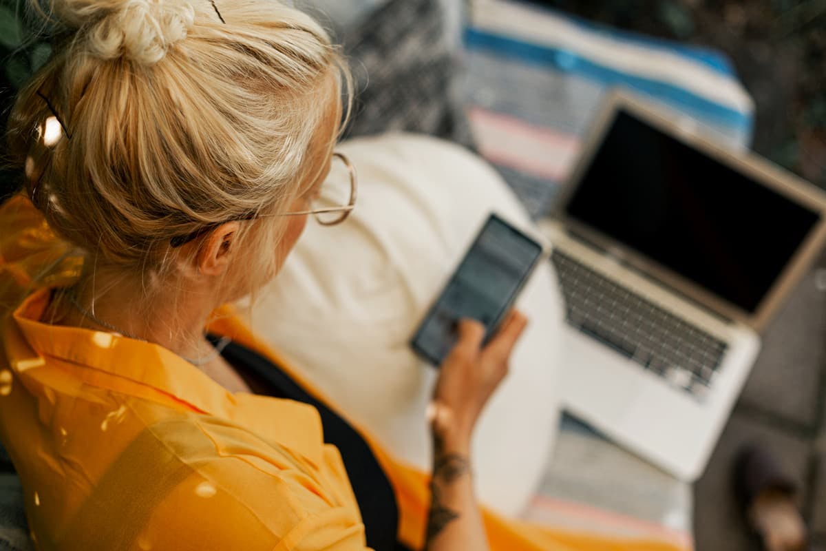 kvinna kollar på telefon och dator