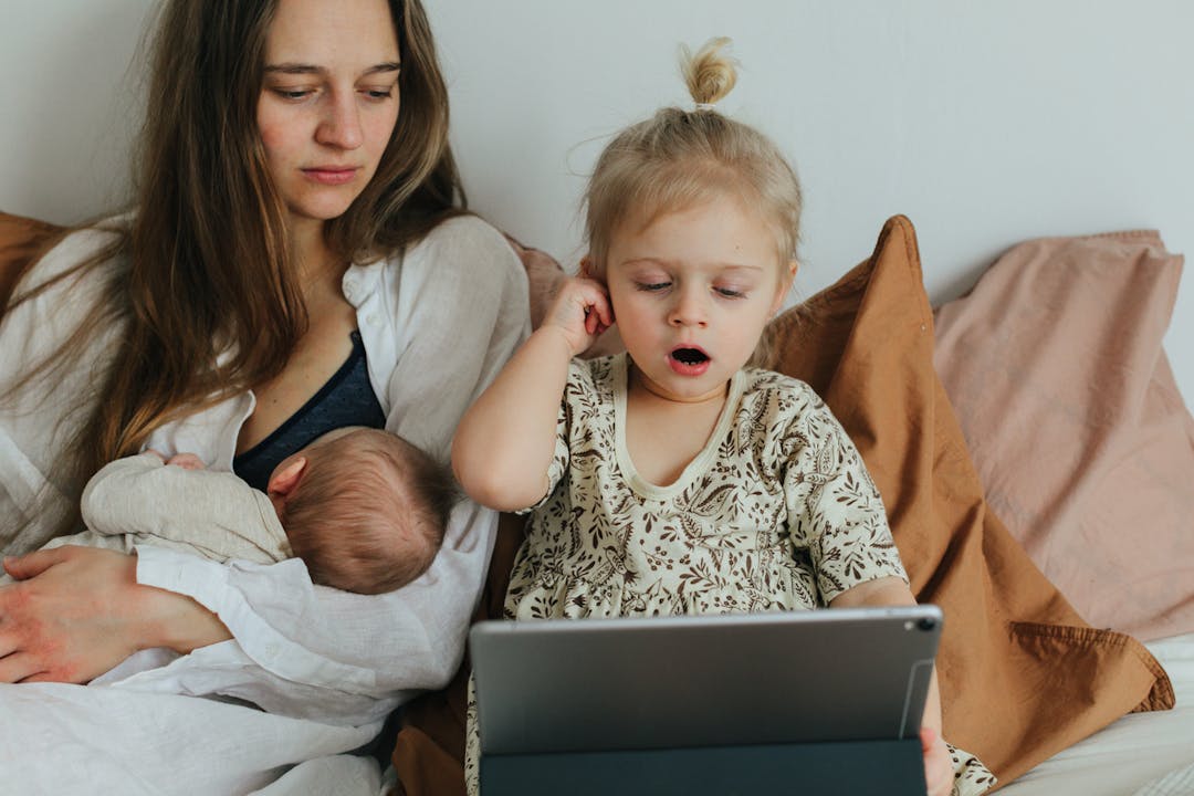mamma ammar bebis och barn kollar på ipad