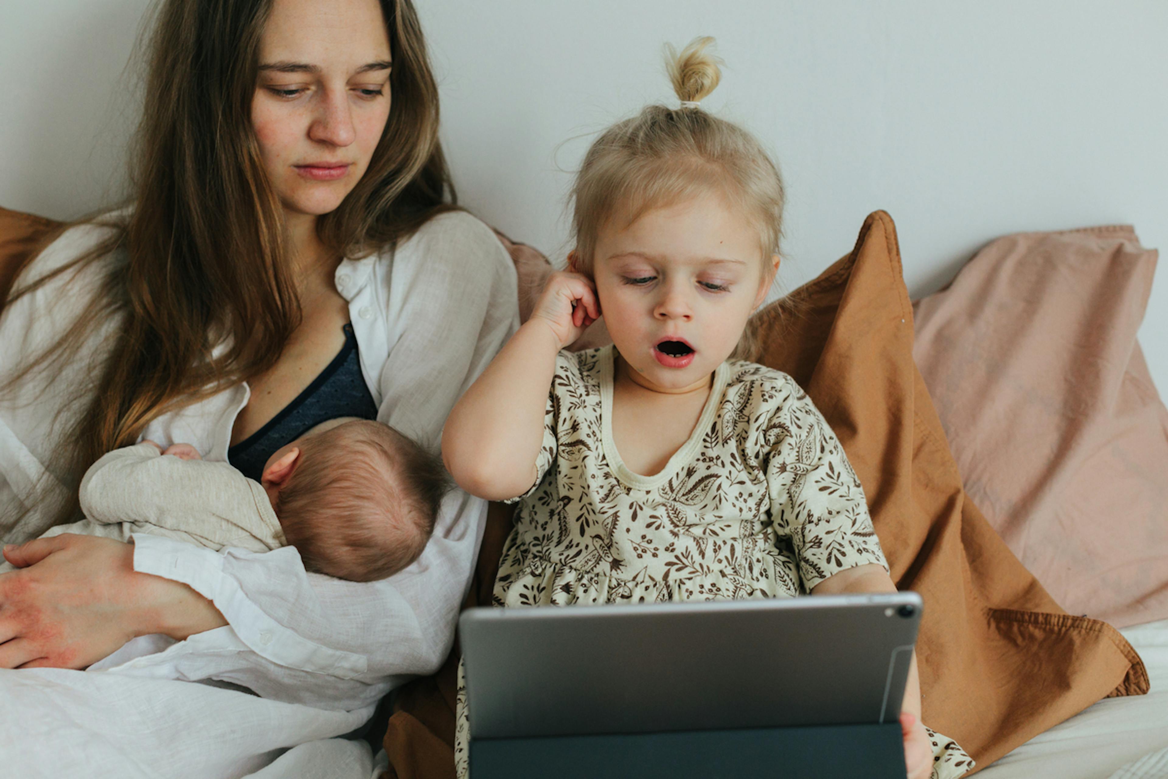 mamma ammar bebis och barn kollar på ipad