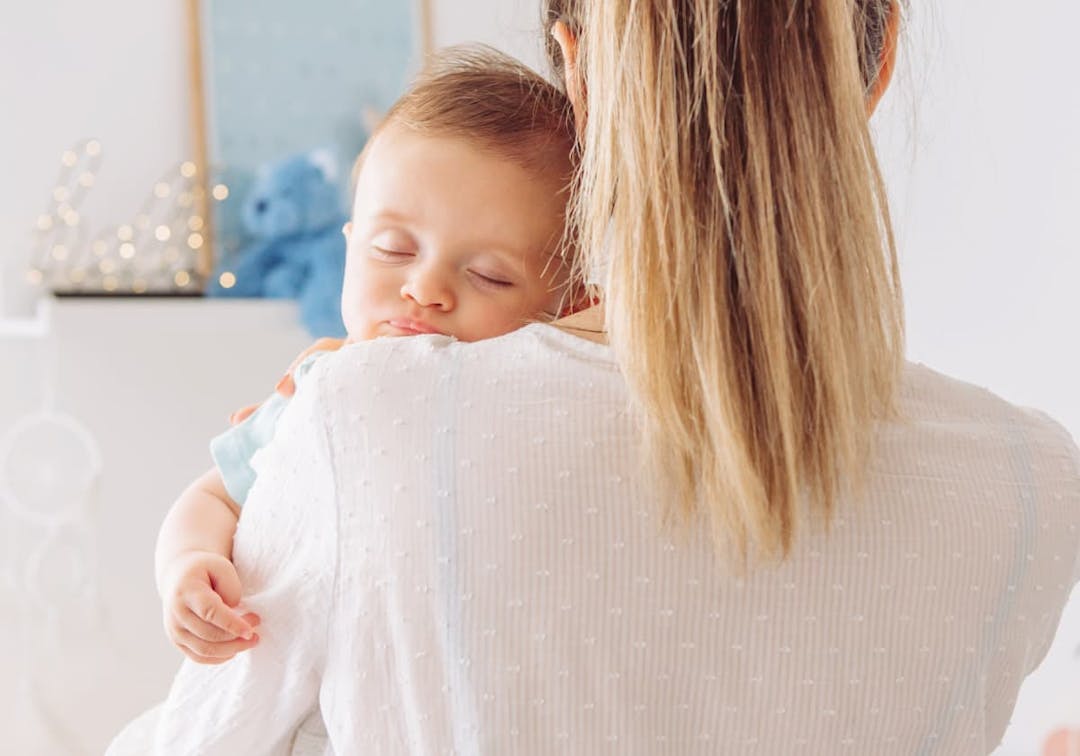 spädbarn som sover i mammas famn