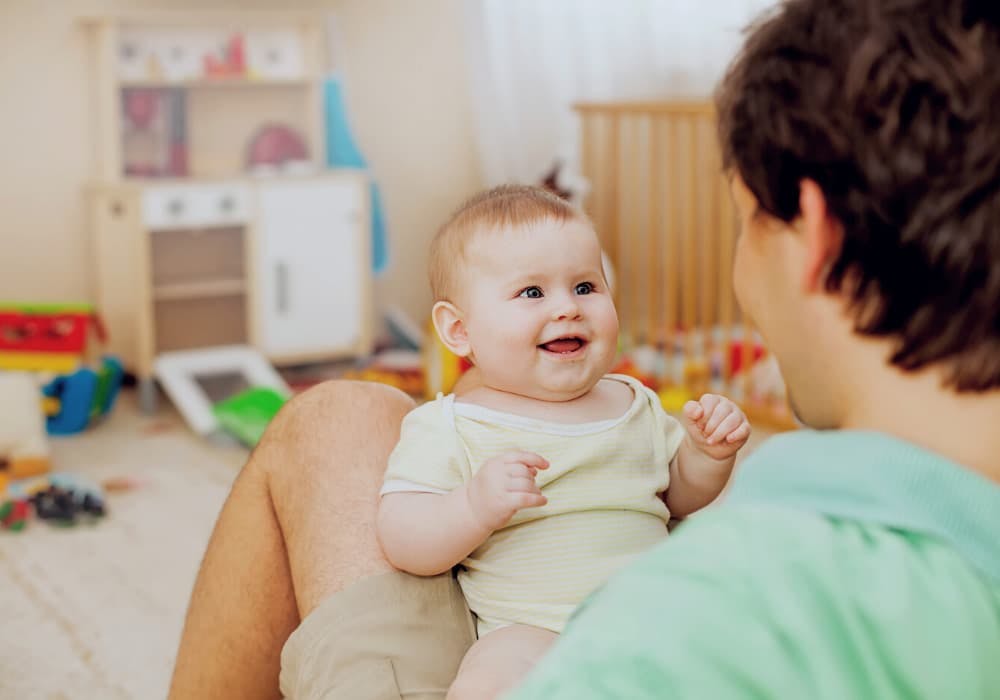 Bebis som sitter i pappas knä och skrattar