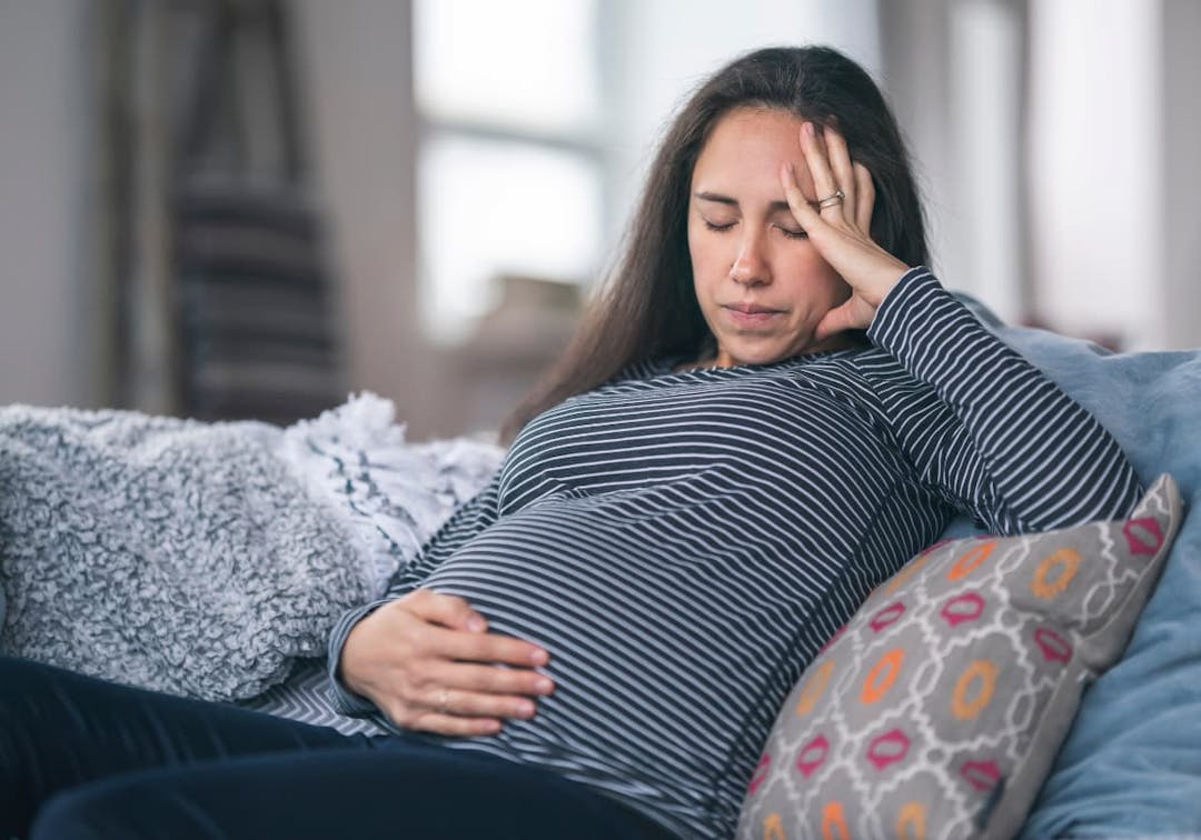 gravid kvinna som håller sig för huvudet