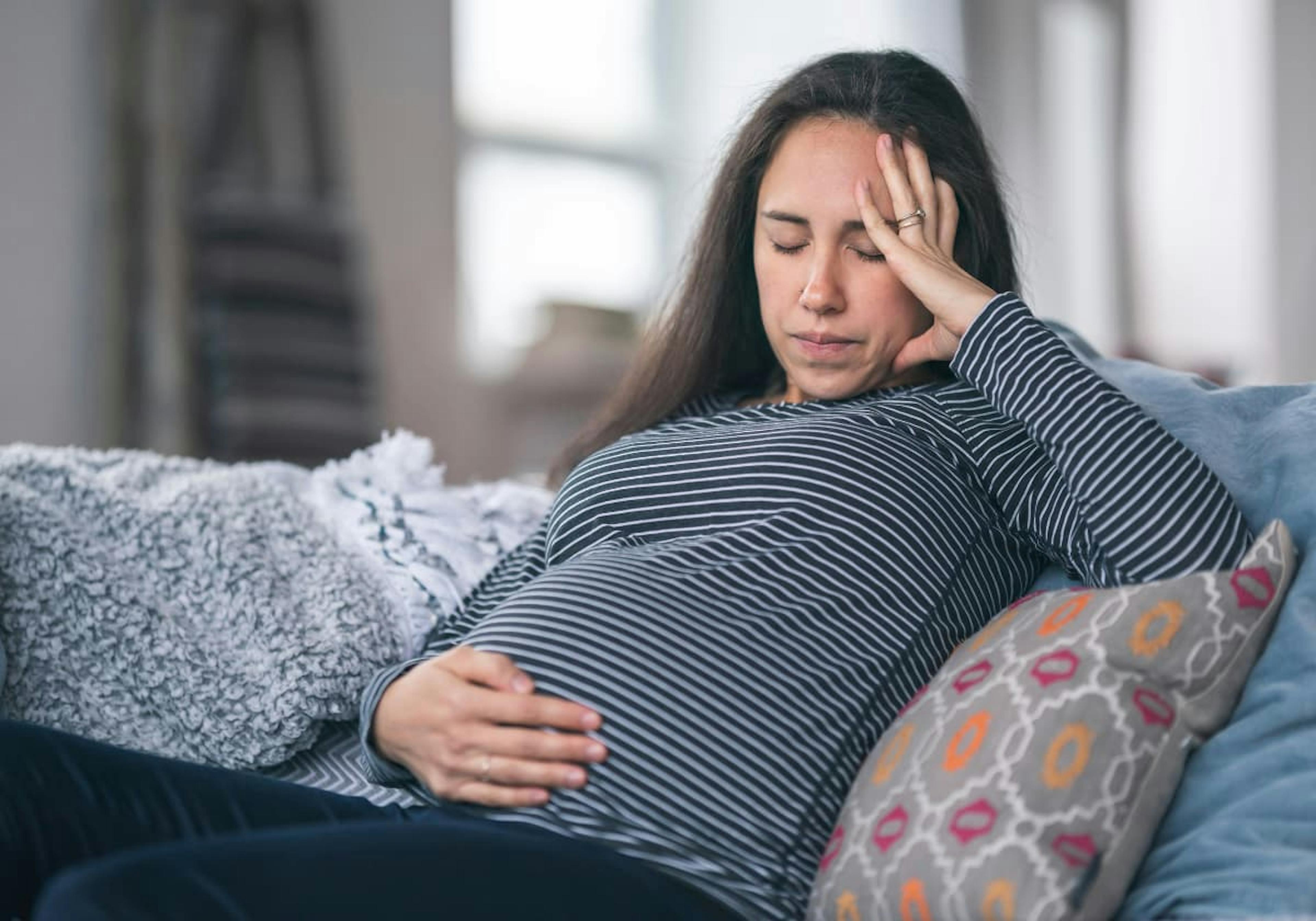 gravid kvinna som håller sig för huvudet